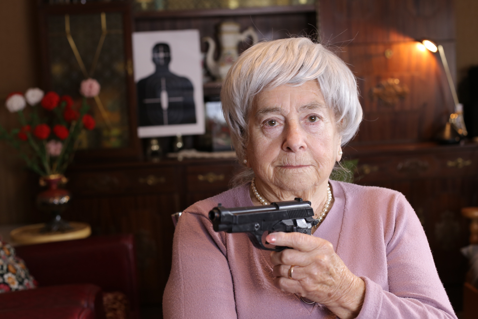 Senior woman holding a gun at home